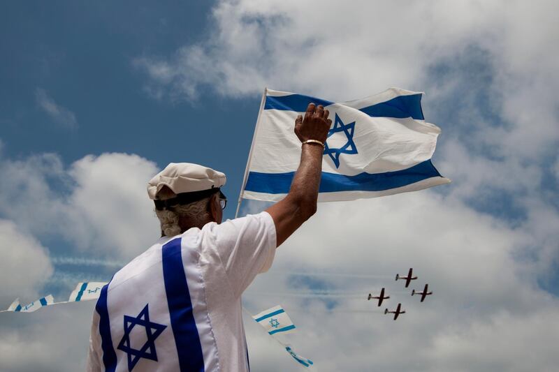 FILE - In this April 26, 2012 file photo, an Israeli waves towards an Israeli air force flyover during Israel's 64th Independence Day anniversary celebrations in Tel Aviv, Israel. As Israel marks the 70th anniversary of statehood starting at sundown Wednesday, April 18, 2018, satisfaction over its successes and accomplishments share the stage with a grim disquiet over the never-ending conflict with the Palestinians, internal divisions and an uncertain place in a hostile region. (AP Photo/Ariel Schalit, File)