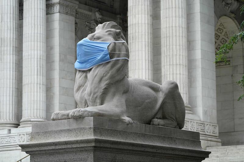 Fortitude, one of the pair of marble lions that sit in front of the New York Public Library's Fifth Avenue and 42nd Street branch in New York, wears a face mask to encourage New Yorkers to continue to follow safety measures in the fight against COVID-19.  AFP