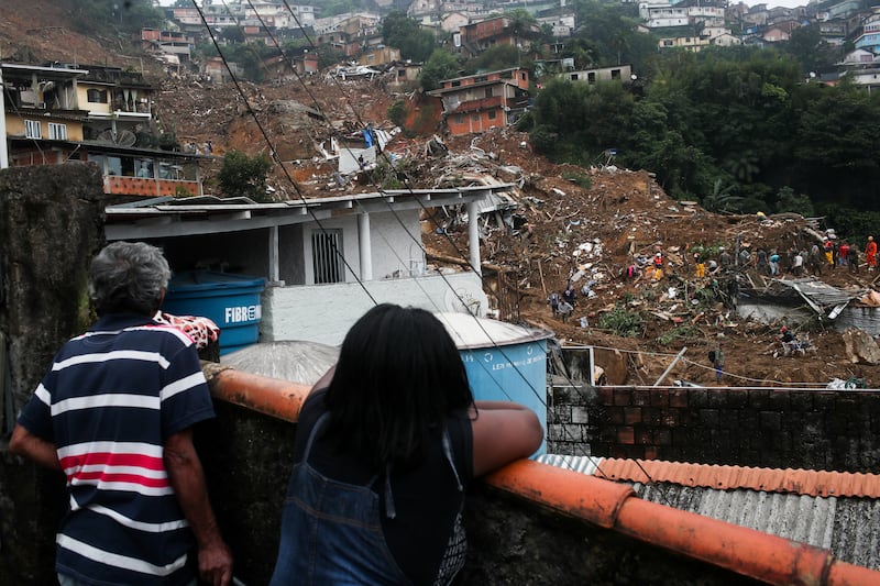 Residents watch as emergency personnel work at a site of a mudslide in Morro da Oficina. Reuters