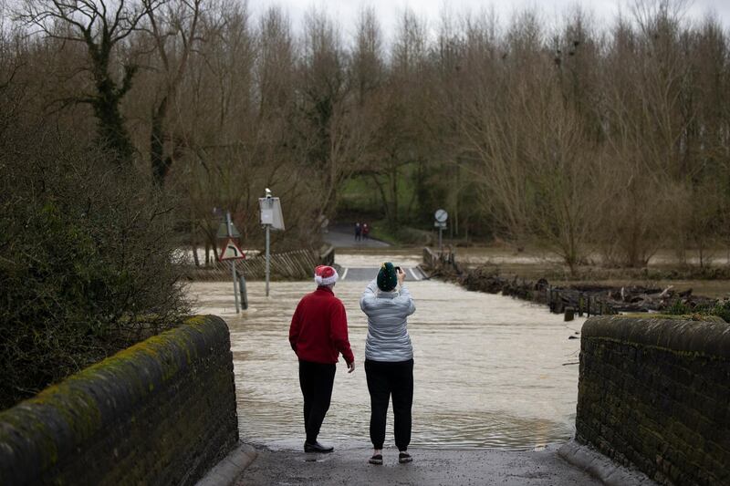 A couple wearing Christmas hats look at high water from a bridge looking over the River Great Ouse towards the village of Harrold in Pavenham, England. Getty Images
