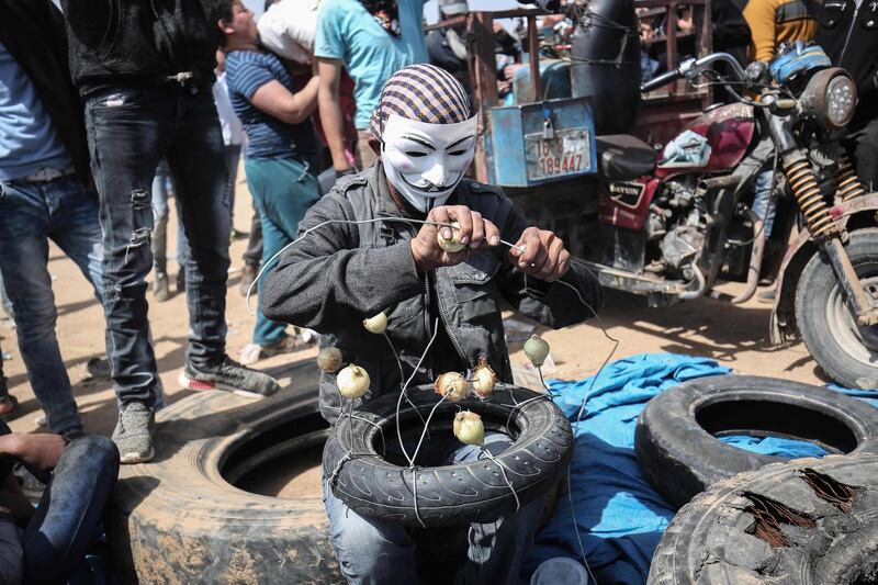 A Palestinian man wearing an Anonymous mask prepares to protest with onions to minimise the effects of tear gas fired by Israeli forces in 2018, a week after similar demonstrations led to violence in which Israeli forces killed 19 Palestinians. AFP