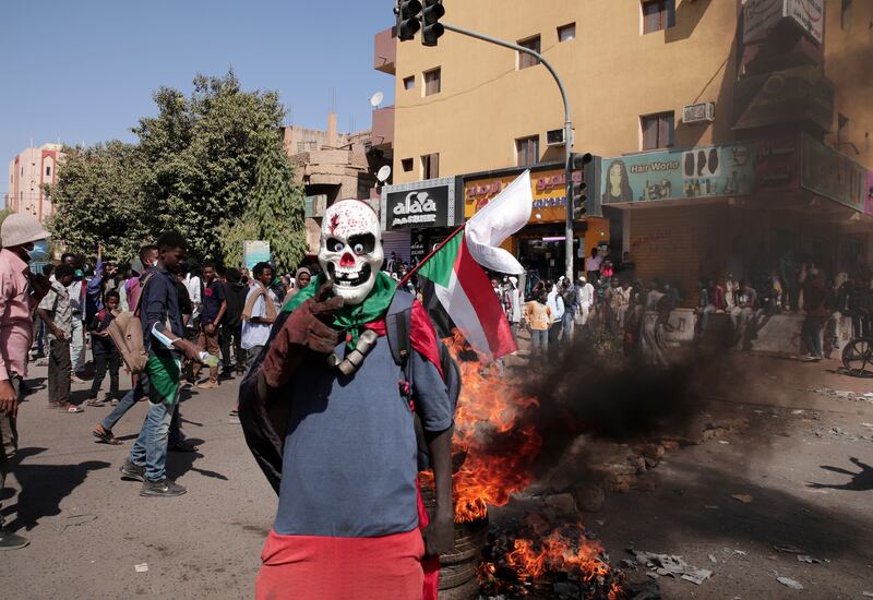 A masked demonstrator stands in front of burning tyres during a protest on Tuesday against the military takeover in Sudan. AP