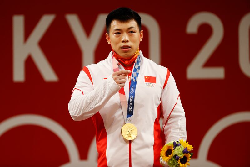 Gold medalitst Lijun Chen of China celebrates on the podium after the men's 67kg weightlifting event.