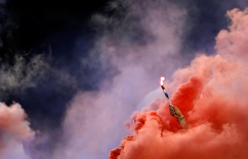A Chivas fan holds a torch as red smoke fills the stands during the second half of the team's Colossus Cup soccer match against River Plate in San Diego.  AP