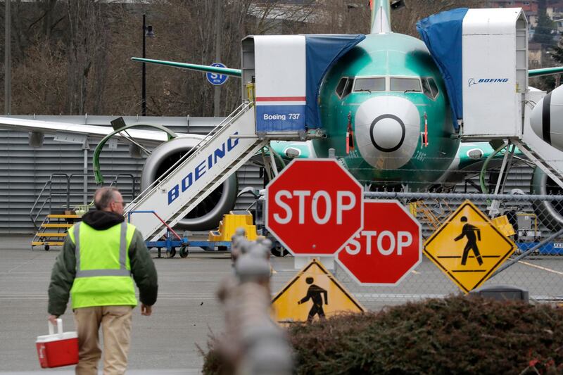 FILE - In this Monday, Dec. 16, 2019 file photo, a Boeing worker walks in view of a 737 MAX jet in Renton, Wash. Shares of Boeing fell before the opening bell on a report that the company may cut production of its troubled 737 MAX or even end production all together. (AP Photo/Elaine Thompson)