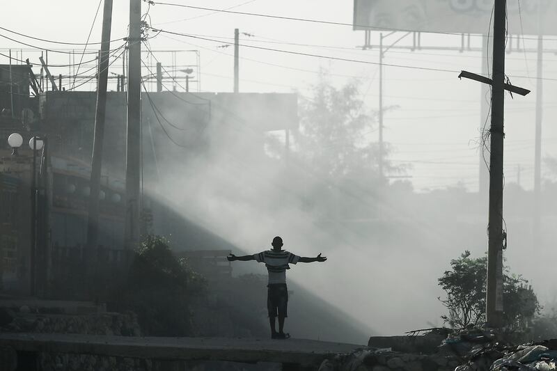 A man stands surrounded by smoke from burning rubbish in Port-au-Prince, amid a general strike and fuel shortages. AP Photo
