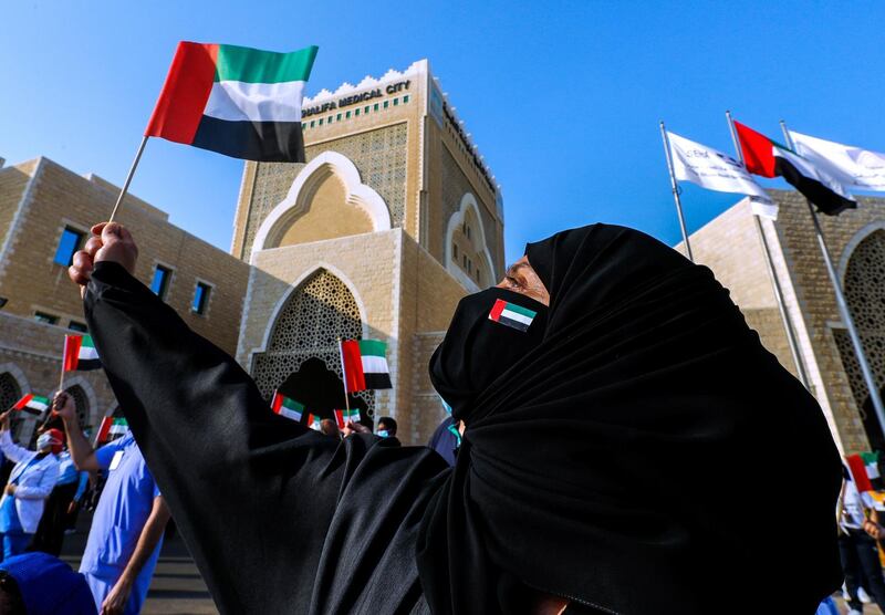 Abu Dhabi, United Arab Emirates, June 21, 2020.   
 Healthcare workers wave the UAE flag during the UAE Air Force's aerobatic display team, Al Fursan,  flies over Sheikh Khalifa Medical City, in an initiative of appreciation by the General Command of the UAE Armed Forces for the nation's medical teams and staff.
Victor Besa  / The National
Section:  NA
Reporter: