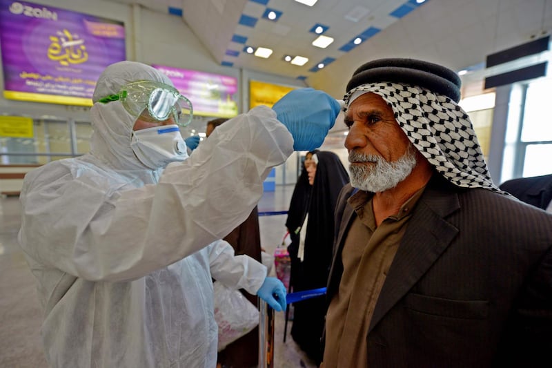 The body temperature of an Iraqi man returning from Iran is measured upon her arrival at the Najaf International Airport on February 21, 2020, after Iran announced cases of coronavirus infections in the Islamic republic.  / AFP / Haidar HAMDANI
