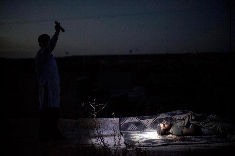 Day or night, the killings continue. Here, at a graveyard, in Aleppo. a man points a torch towards the body of a recently killed man.