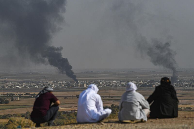 People look on as smoke rises from the Syrian town of Ras al-Ain, in a picture taken from the Turkish side of the border in Ceylanpinar, on the third day of Turkey's military operation against Kurdish forces. AFP