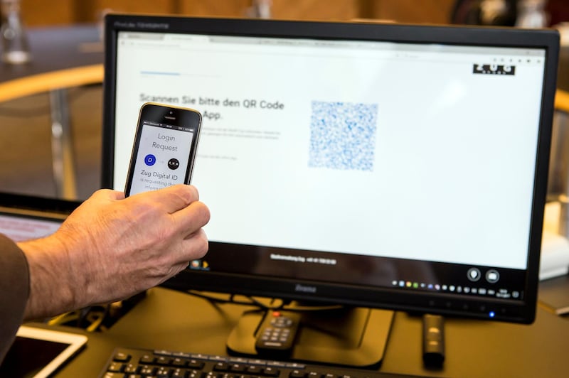 epa06330660 A mobile phone and a computer screen are seen during the demonstration of a blockchain-based digital ID in Zug, Switzerland, 15 November 2017. The city of Zug now offers all residents the opportunity to get a digital identity. This is based on an app and is linked to the Ethereum Blockchain.  EPA/ALEXANDRA WEY