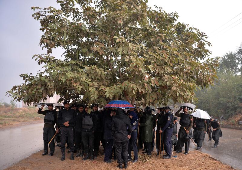 Pakistani policemen crouch under a tree in Islamabad to escape the rain. Aamir Qureshi / AFP Photo