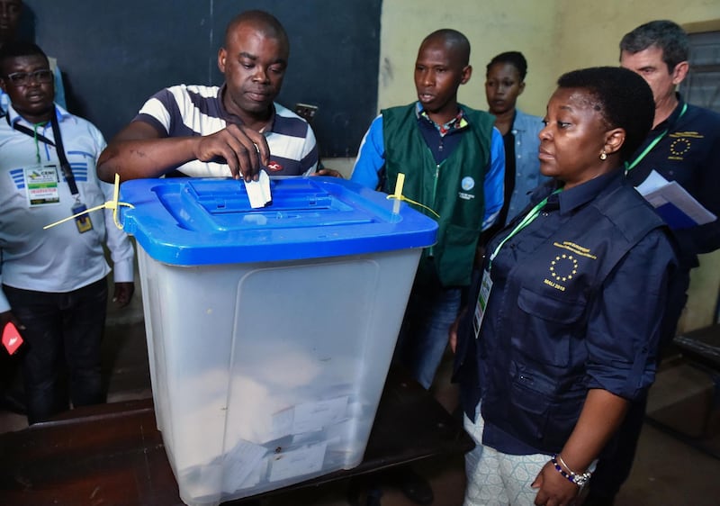 A man casts his vote next to the head of the European Union Election Observer mission in Mali, Cecile Kyenge (R), at a polling station on August 12, 2018 in Bamako during the counting of the votes after the second round of Mali's presidential elections. - Malians were voting on August 12 in a presidential runoff likely to see the incumbent president returned to office despite criticism of his handling of the country's security crisis and allegations of election fraud. (Photo by ISSOUF SANOGO / AFP)