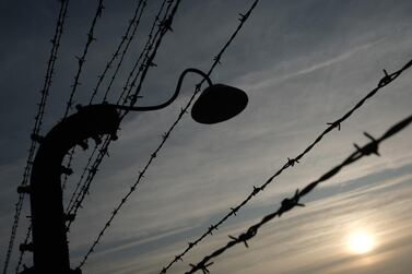 Barbed wire and a floodlight stand silhouetted against the sky at the former Auschwitz-Birkenau German concentration camp. Getty