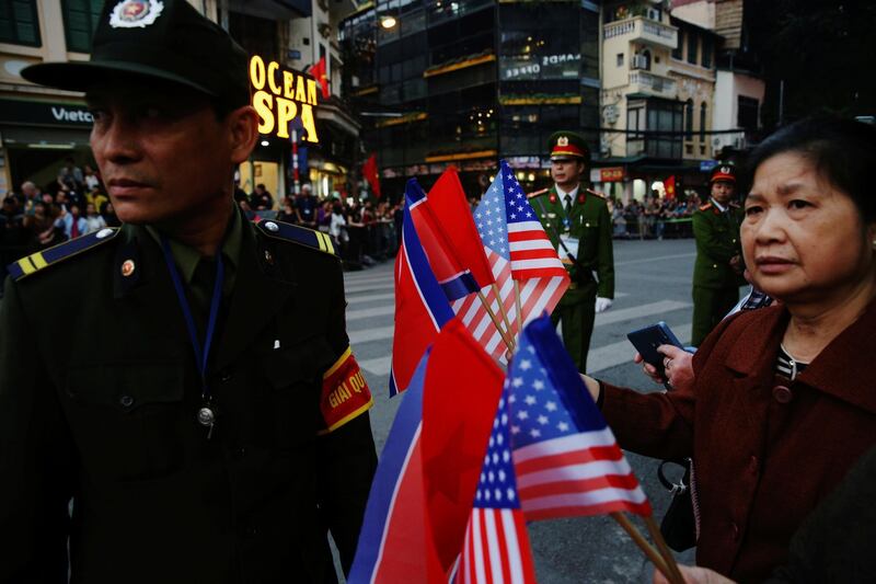 A woman holding North Korean and US flags stands near the Metropole Hotel. Reuters