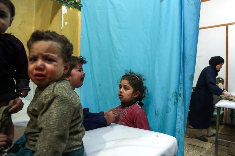 A Syrian girl looks at another crying child sitting on a hospital bed in a make-shift clinic in the rebel-held town of Douma, in the besieged Eastern Ghouta region on the outskirts of the capital Damascus, after they arrived to receive medical attention following reported regime bombardment on the area. Hamza Al-Ajweh / AFP