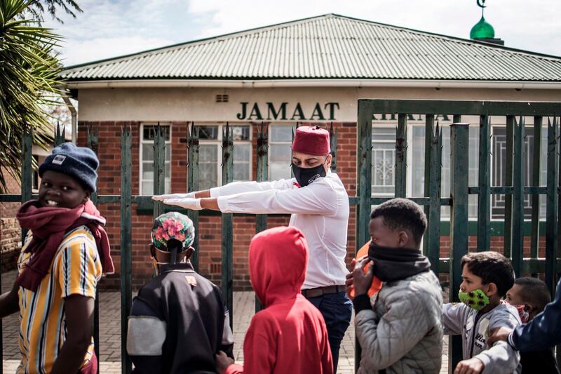 Rashad, a volunteer with the grassroots charity Hunger has no Religion, instructs children to maintain social distancing in Johannesburg during an Eid Al Fitr meal distributed to hundreds in the neighbourhoods of Westbury and Coronationville.  AFP