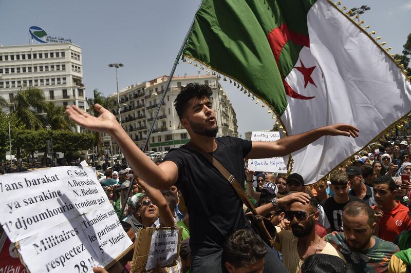 Algerian demonstrators wave a national flag and carry placards staing their demands as they take part in a protest in the streets of the capital Algiers.  AFP