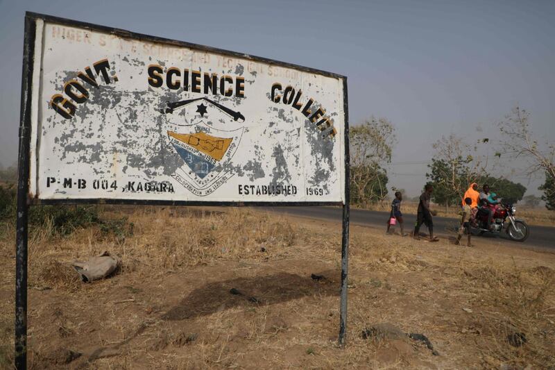 People walk past a sign for the Government Science College, in Kagara, where gunmen kidnapped 42 people on February 17. On February 23, the abducted pupils, staff and family members were still missing. AFP