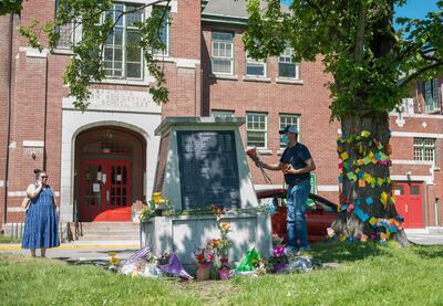 People lay flowers in front of the administration building at the former Kamloops Indian Residential School, after the remains of 215 children, some as young as three years old, were found at the site in Kamloops, British Columbia, Canada May 29, 2021.  REUTERS/Dennis Owen