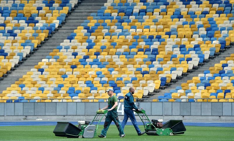 Groundstaff cut the playing surface of The NSC Olimpiyskiy Stadium in Kiev, on May 14, 2018, ahead of the 2018 UEFA Champions League Final football match between Liverpool and Real Madrid. Sergei Supinsky / AFP Photo