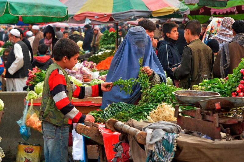 An Afghan burqa clad woman buys vegetable at a market in Kabul on December 9, 2019. / AFP / NOORULLAH SHIRZADA
