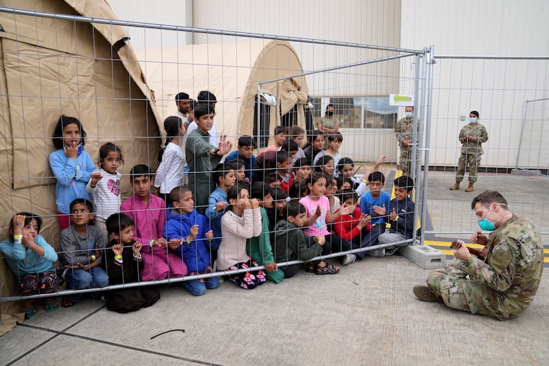 A US soldier entertains Afghan children at the Ramstein US Air Base, Germany. AP Photo