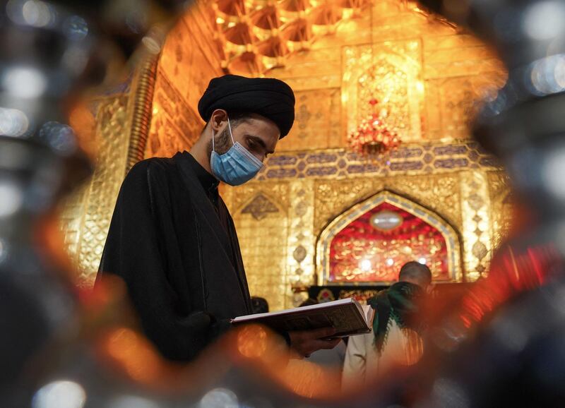 A Shiite cleric reads the Koran, Islam's holy book, during prayer rituals of Laylat al-Qadr (Night of Destiny) which marks the night in which the holy Koran was first revealed to the Prophet Mohammed, at the Imam Ali shrine in the Iraqi city of Najaf, on May 1, 2021. / AFP / Ali NAJAFI
