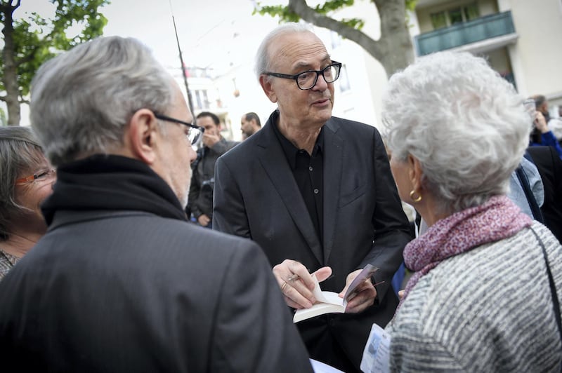 French literature Nobel prize writer Patrick Modiano signs autographs during the inauguration of the street "Promenade Dora Bruder" on June 1, 2015 in Paris. Dora Bruder was a French Jewish woman who died in the Nazi death camp Auschwitz.  AFP PHOTO / MARTIN BUREAU (Photo by MARTIN BUREAU / AFP)