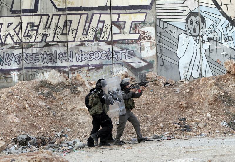 Israeli soldiers fire tear gas towards strone throwers demonstrating against the Israeli military offensive on the Gaza Strip at the Qalandia checkpoint, in the Israeli occupied West Bank, on November 18, 2012 . Israel's Foreign Minister Avigdor Lieberman said that Israel would not negotiate a truce with Gaza Strip's Hamas rulers as long as rocket fire continues from the Palestinian enclave AFP PHOTO/AHMAD GHARABLI (Photo by AHMAD GHARABLI / AFP)