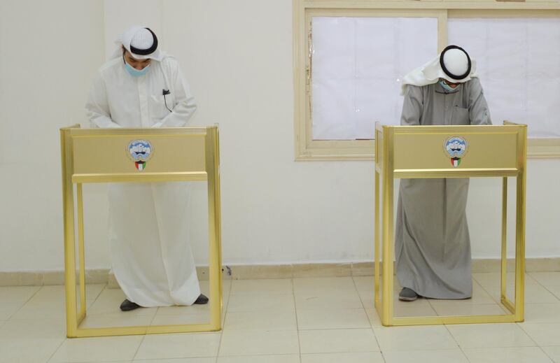 People ware wearing protective masks cast their votes at a polling station in Kuwait City. EPA