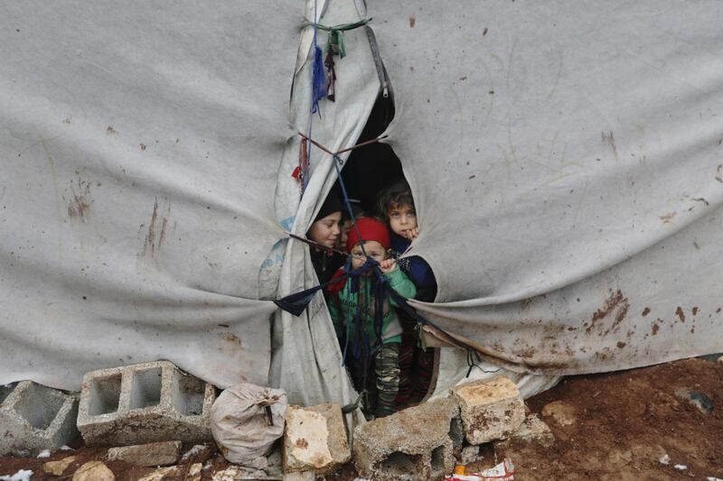 Internally displaced children look out from a tent in Azaz, Syria. REUTERS