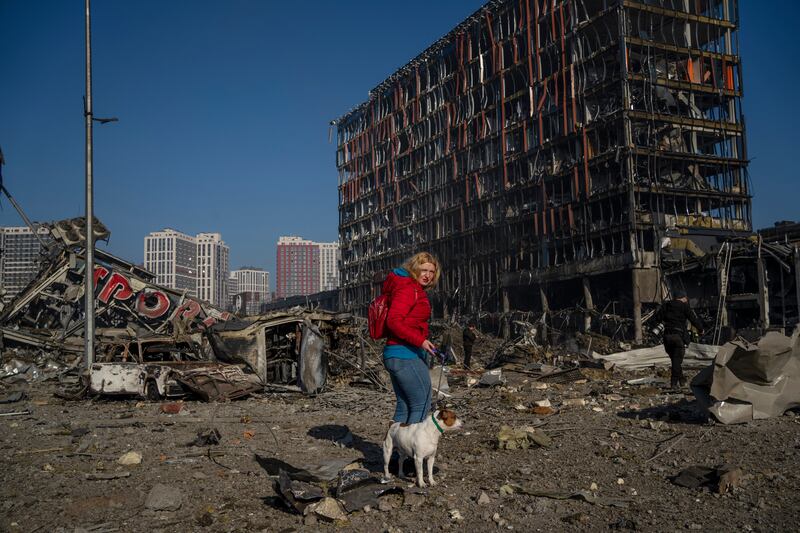 Irina Zubchenko walks her dog Max amid the destruction caused by the shelling of a shopping center in Kyiv. AP