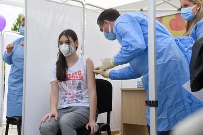 A girl gets a Pfizer BioNTech COVID-19 vaccine in Bucharest, Romania, Wednesday, June 2, 2021. Romania has started the vaccination campaign for children between the ages of 12 and 15. (AP Photo/Andreea Alexandru)