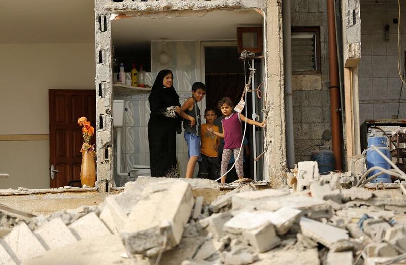 A Palestinian woman and children stand in a room of their house whose facade was destroyed overnight by Israeli airstrikes on August 26, 2014 in Gaza City. The UN estimates that about a quarter of the 1.8 million inhabitants of Gaza have been displaced by fighting between Hamas militants and Israel since fighting started on July 8. Mohammed Abed/AFP Photo