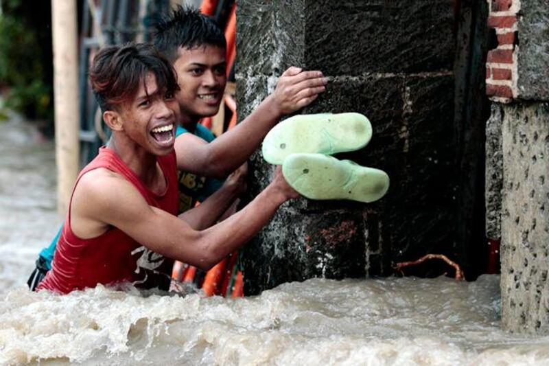 Filipino men struggle to cross strong currents as floodwaters rise at a residential area in Las Pinas, south of Manila, Philippines Monday, Aug. 19, 2013. Torrential rains brought the Philippine capital to a standstill Monday, submerging some areas in waist-deep floodwaters and making streets impassable to vehicles while thousands of people across coastal and mountainous northern regions fled to emergency shelters. (AP Photo/Aaron Favila)