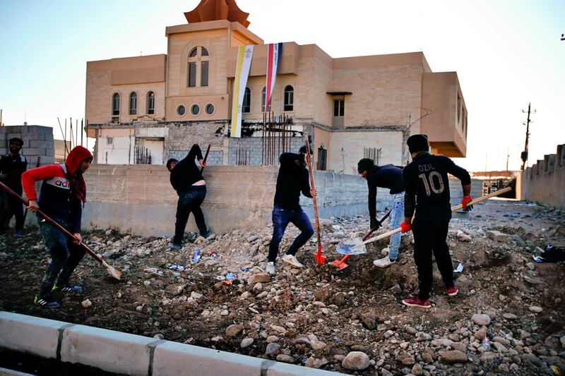 People fix a street destroyed during clashes against the Islamic State militants in Qaraqosh, Iraq. AP Photo