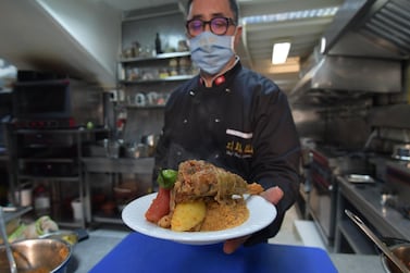 Tunisian chef Taieb Bouhadra presents a prepared traditional Tunisian lamb couscous dish at a restaurant in the Medina (old town) of Tunisia's capital Tunis on December 16, 2020. Couscous, the Berber dish beloved across northern Africa's Maghreb and Sahel regions, has become a global foodie favourite now found on the shelves of organic supermarkets everywhere. Love it or hate it, but on December 16 the grain staple passed another culinary milestone when the UN cultural organisation honoured it as part of the world's intangible cultural heritage. / AFP / Fethi Belaid