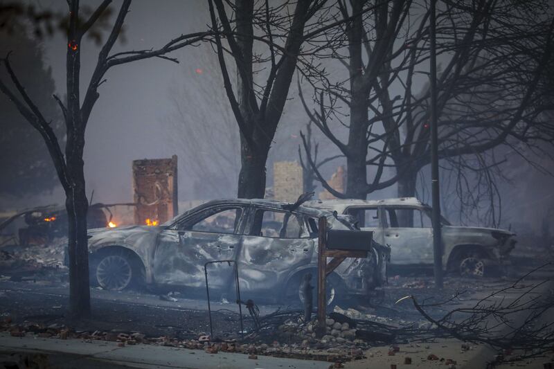Burnt-out vehicles sit amid the smoke and haze in the Centennial Heights neighbourhood of Louisville. AFP