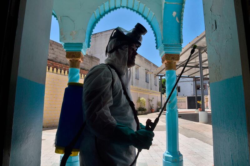 A civil volunteer from the Hocine Dey commune sprays disinfectant outside the Abou Hanifa Enouemane mosque in the capital Algiers, Algeria.   AFP