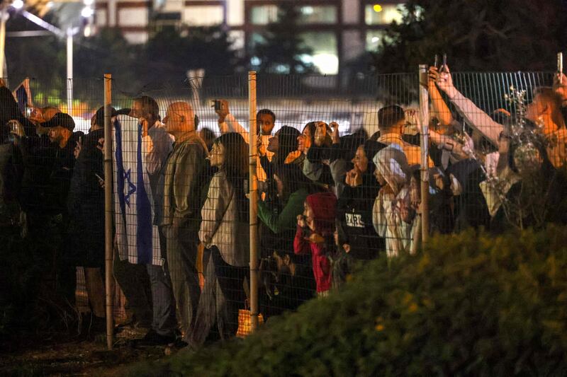 Israelis look on as a helicopter with released hostages prepares to land in Tel Aviv. AFP