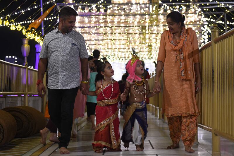 Children dressed as Krishna and Goddess Radha walk along with their parents. AFP