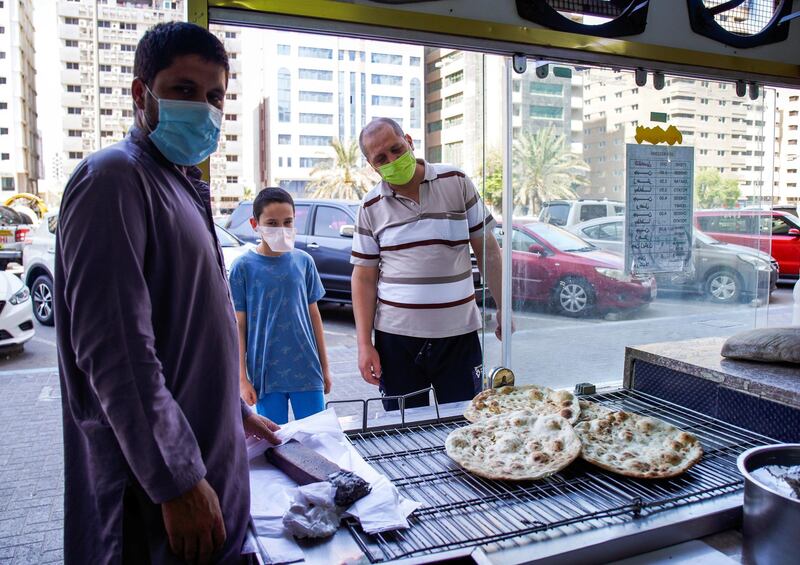 Abu Dhabi, United Arab Emirates, September 18, 2020.  Mustaffa, eleven, waits for his bread to be baked with his uncle Abdul Qader outside the Naser Bader Bakery.Victor Besa /The National
Section:  NA/Standalone.