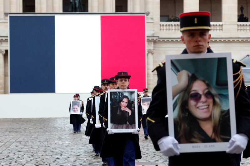 Presidential guards hold portraits of the French victims of the October 7 attack. AP