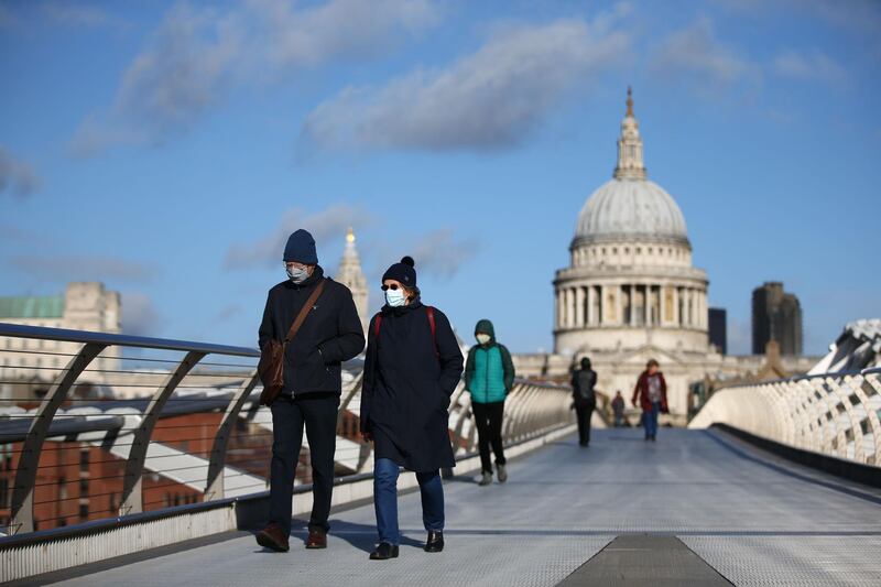 Pedestrians wearing masks because of the coronavirus pandemic cross Millennium Bridge with St Paul's Cathedral in the background in central London on November 3, 2020 as England prepares to head into a second coronavirus lockdown in an effort to combat soaring infections. England will head into a second national lockdown on November 5. / AFP / Hollie Adams
