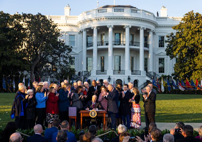 Mr Biden, surrounded by lawmakers, signs the bipartisan Infrastructure Investment and Jobs Act on the South Lawn of the White House on November 15. EPA