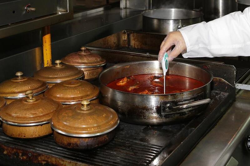 A Dubai Municipality food inspector checks dishes being cooked at a restaurant. Courtesy Dubai Municipality