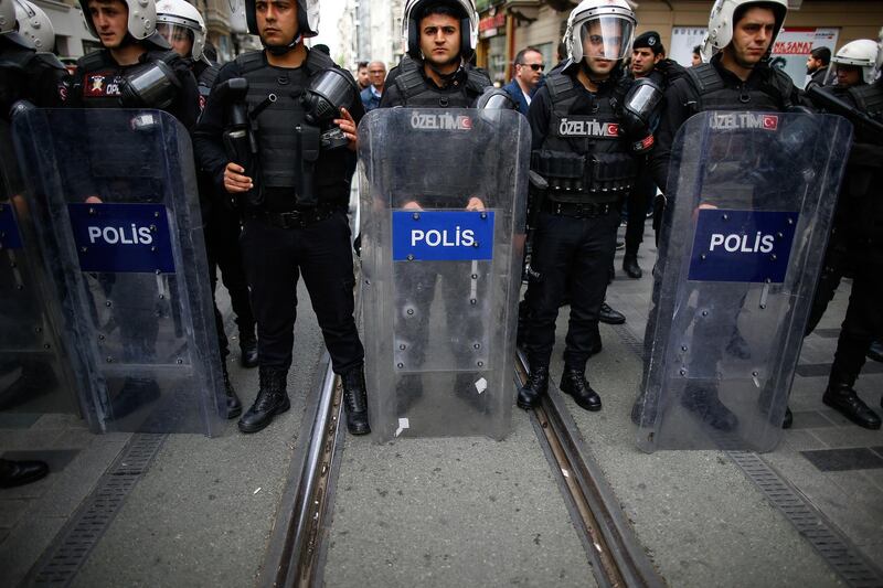 FILE - In this file photo dated Monday, April 16, 2018, Turkey's police officers look on as supporters of Turkey's main opposition Republican People's Party, CHP, gather to protest near central Istanbul's Taksim Square.  Turkey's controversial two-year-long state of emergency is scheduled to end at midnight Wednesday July 18, 2018, but the government is set to introduce new anti-terrorism laws it says are needed to deal with continued security threats. (AP Photo/Emrah Gurel, FILE)