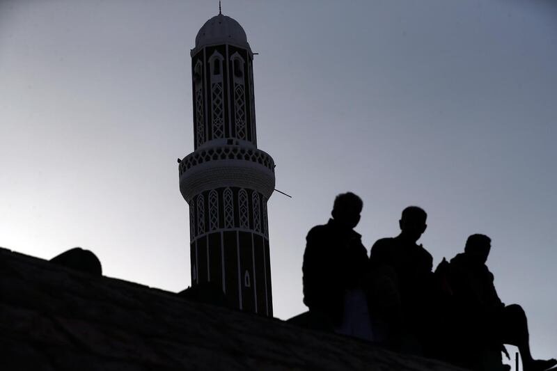 The silhouette of Yemenis sitting in front of a kiln-baked brick-built minaret tower of a historic mosque in Sanaa, Yemen.  EPA