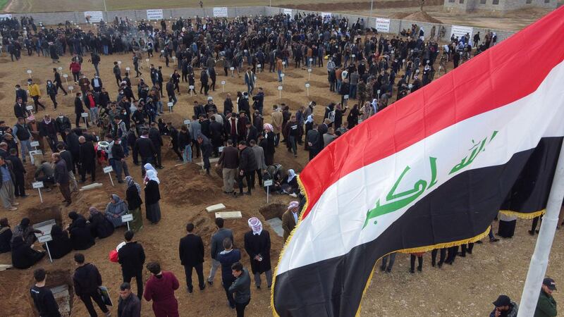 Mourners gather around graves during a mass funeral for Yazidi victims of ISIS in the northern Iraqi village of Kocho. AFP